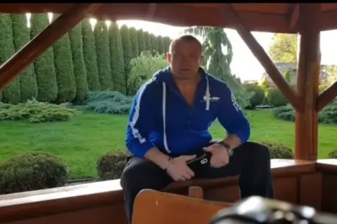 Mariusz Pudzianowski w swojej posiadłości, gdzie mieszka. W tle zadbany ogród z żywopłotem.