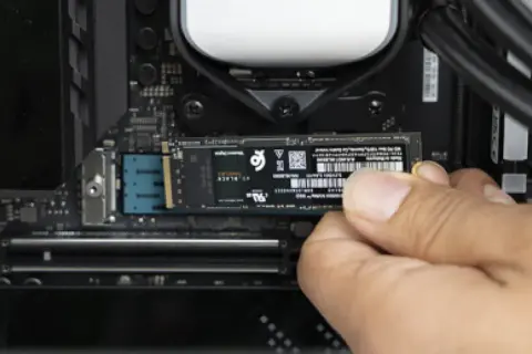 Dłoń instaluje dysk M.2 PCIe na płycie głównej komputera.