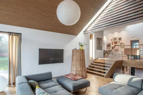 Gemütliches Wohnzimmer in einem Split-Level-Haus mit Holzakzenten, Treppen und gemütlichen Sofas.