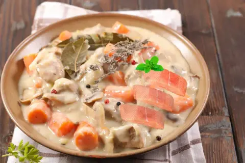 Délicieuse blanquette de poisson crémeuse avec carottes, champignons, herbes et garnie de tranches de saumon frais.