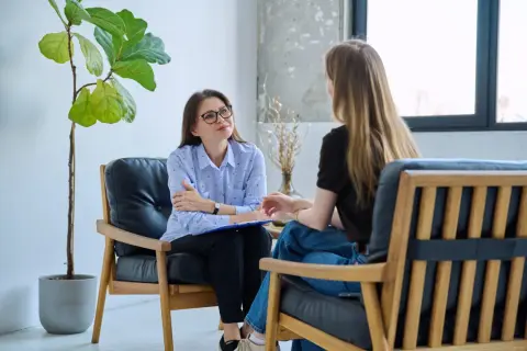 Terapeuta rozmawia z pacjentem, który może mieć zespół Aspergera. W tle roślina i okno.
