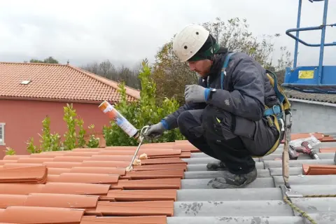 Trabajador aplicando espuma para impermeabilizar tejado de tejas.