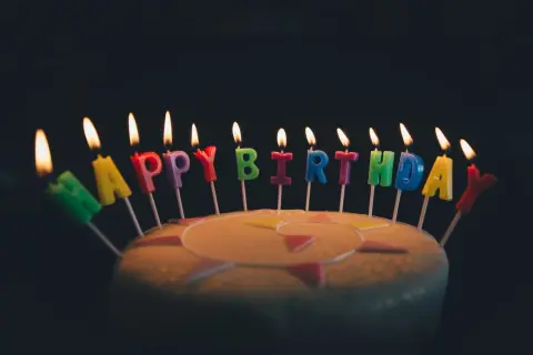 Płonące świeczki w kształcie liter tworzą napis "Happy Birthday". Idealne na życzenia urodzinowe po angielsku.