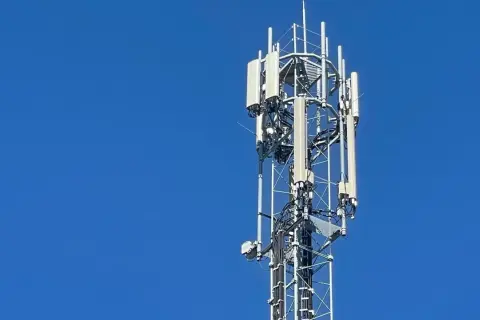 Wieża telekomunikacyjna z antenami LTE na tle błękitnego nieba.