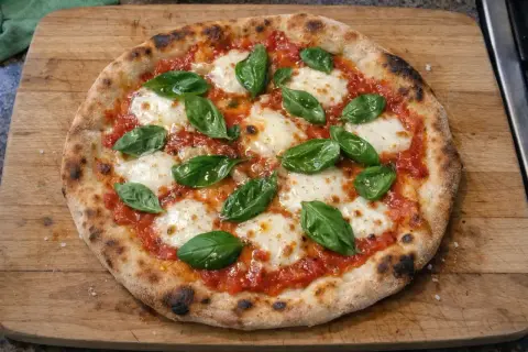 En hemmagjord pizza med tomatsås, mozzarella och färsk basilika. Ett perfekt pizza recept för en mysig kväll.