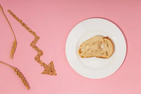 Strzałka z ziaren pszenicy wskazuje na kromkę chleba na talerzu, symbolizując uczulenie na gluten i potrzebę unikania go.