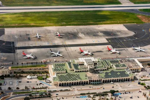 Lotnisko na Malcie, z samolotami Ryanair i Malta Air na płycie. Widok z lotu ptaka ukazuje ruchliwy terminal i pasy startowe.