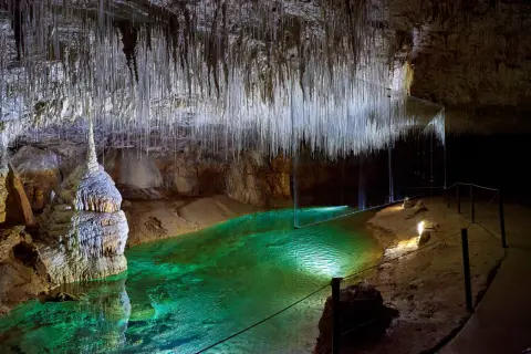 Émerveillement dans la grotte de Thaïs : stalactites fines comme des fils, eau émeraude et formations rocheuses spectaculaires.