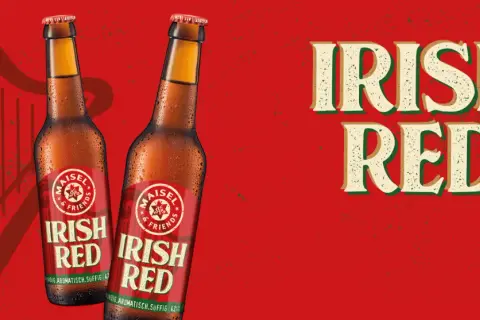 Zwei Flaschen "Irish Red" Bier vor rotem Hintergrund mit Harfenmotiv. Was ist Rotbier? Dieses Irish Red Ale ist vollmundig, aromatisch und süffig.