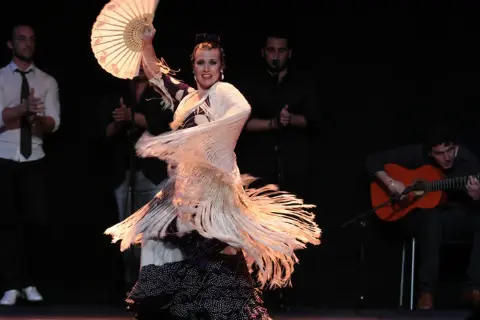 Bailaora con abanico y mantón, evocando el espíritu de Lorca y el flamenco, acompañada por guitarrista y palmeros.
