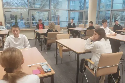 Uczniowie podczas mscdn konkursy przedmiotowe. Młodzi ludzie siedzą przy stołach, skupieni na zadaniach.