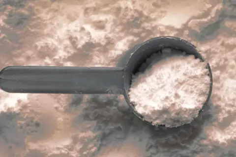 Misurino pieno di polvere bianca, che evoca il significato delle proteine idrolizzate per un rapido recupero muscolare.