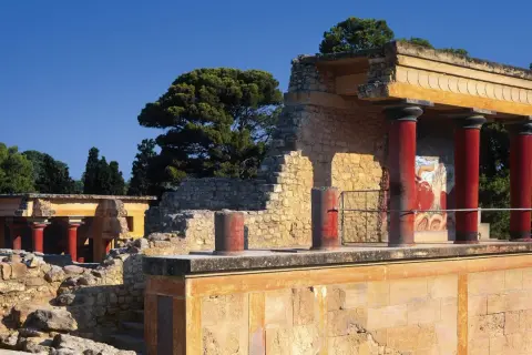 Ruinas del palacio de Cnosos con sus icónicas columnas rojas y un fresco de toro.