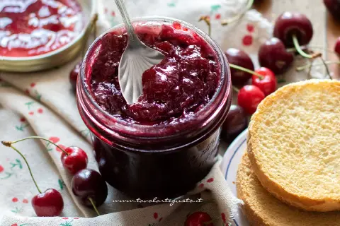 Un barattolo pieno di deliziosa marmellata di ciliegie, pronto per essere spalmato su fette biscottate.