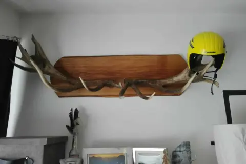 Une idée déco avec bois de cerf : des bois imposants fixés sur une planche de bois, supportant un casque de ski jaune vif.