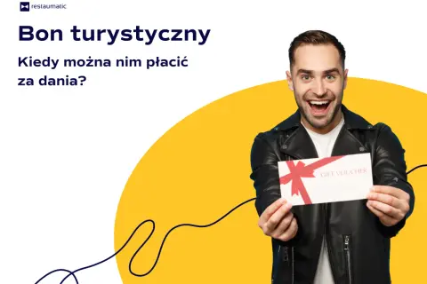 Uśmiechnięty mężczyzna trzyma bon podarunkowy. Czy bon turystyczny można wykorzystać w restauracji na pyszne dania?