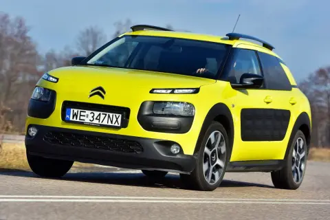 Żółty Citroen C4 Cactus na drodze. Kierowca testuje auto, zbierając pozytywne opinie o jego komforcie i oryginalnym wyglądzie.
