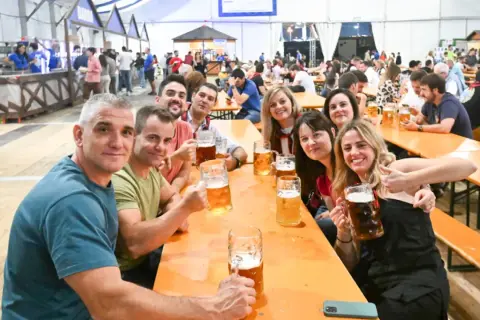 Amigos brindando con jarras de cerveza en el oktober valdespartera. Ambiente festivo y sonrisas.