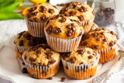 Stos muffinek bananowo czekoladowych, pachnących domem i słodyczą, gotowych do zjedzenia.
