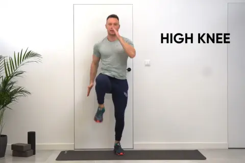 Mężczyzna wykonuje ćwiczenie high knees na macie treningowej.