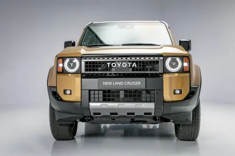 Złoty Toyota Land Cruiser 2020 z okrągłymi światłami i napisem "NEW LAND CRUISER" na grillu.