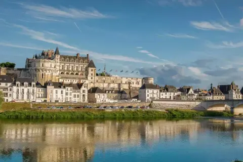 Le majestueux château d'Amboise se dresse fièrement au-dessus de la Loire, ses tours et façades blanches reflétant la lumière du soleil sur l'eau paisible.