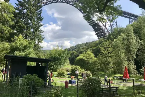 Familien genießen ein **adventure minigolf nrw** unter der imposanten Eisenbahnbrücke.
