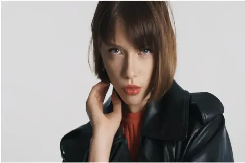 Mujer con un moderno corte bob, labios rojos y chaqueta de cuero negra.