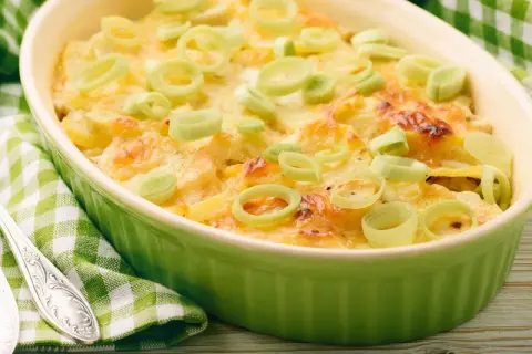 Ein köstlicher, schneller Auflauf mit Lachs und Kartoffeln, überbacken mit Käse und garniert mit Lauchringen.