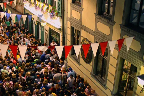 Buntes Treiben beim Bamberger Volksfest. Girlanden schmücken die Gasse, Menschenmassen feiern ausgelassen.