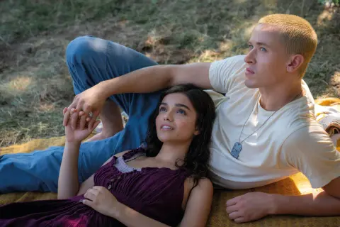 Ein junges Paar liegt im Gras. Sie halten Händchen, ein zarter Moment vor dem Hintergrund von "Die Tribute von Panem 5".
