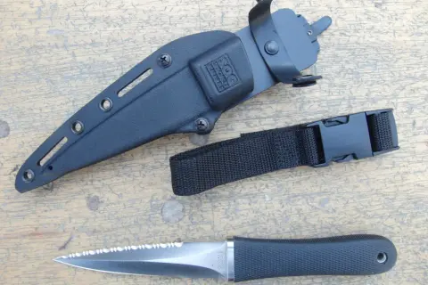 Daga táctica SOG con funda negra y correa de sujeción. Hoja de acero con sierra.