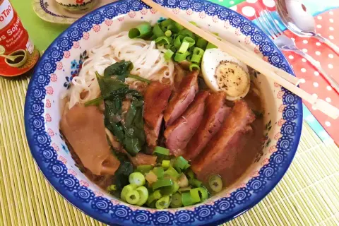 Aromaticzny ramen z kaczki z makaronem ryżowym, jajkiem na twardo, szpinakiem i szczypiorkiem.