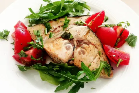 Spiedini di pesce spada in padella con pomodorini freschi e rucola, un piatto leggero e saporito.