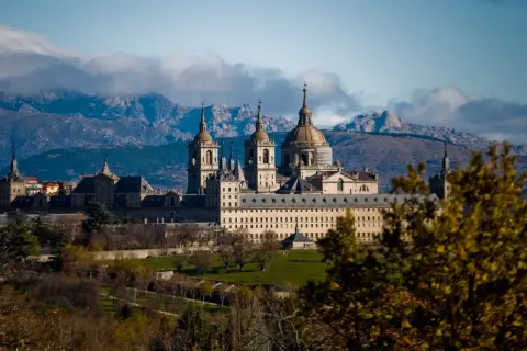 Impresionante Monasterio de El Escorial, un lugar clave que ver en la Comunidad de Madrid, con montañas nevadas al fondo.
