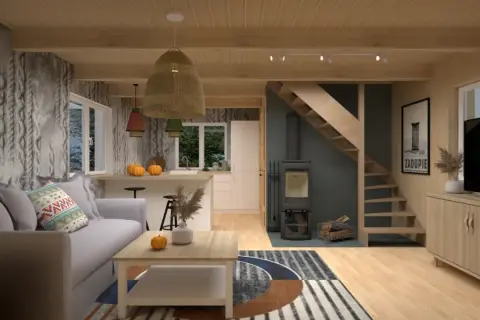 Przytulne wnętrze małego domku letniskowego: szara sofa, drewniane belki, kuchnia, piecyk i schody. Inspiracja, jak urządzić mały domek letniskowy.