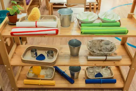 Montessori ideas: Shelves with practical life activities like pouring, washing, and transferring. Includes buckets, bowls, cups, and sponges.
