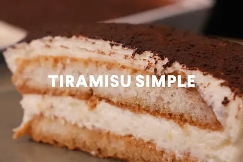 Une part généreuse de tiramisu simple, parfait pour 10 personnes, avec ses couches de biscuits imbibés et de crème onctueuse, saupoudré de cacao.