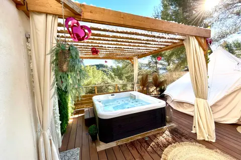 Jacuzzi extérieur sous pergola, décoré de cœurs, près d'une yourte dans les Alpes-Maritimes. Détente et nature.