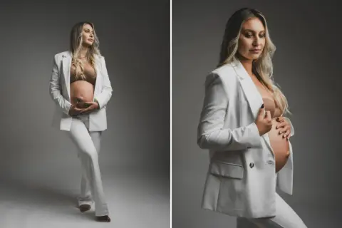 Elegancka sesja ciążowa w domu: przyszła mama w białym garniturze czule obejmuje brzuszek. Pomysły na stylowe zdjęcia.