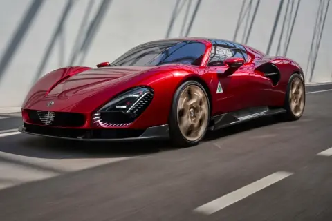 Błyszczący, czerwony Alfa Romeo 33 pędzi po drodze, jego złote felgi wirują w ruchu.