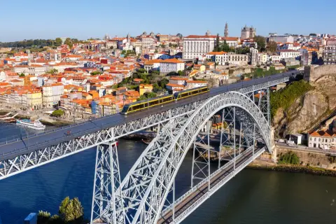 Most zwodzony w Porto z żółtym tramwajem, widok na miasto i rzekę. Szukasz informacji o wino porto cena?