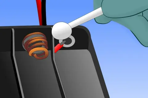 Mit einem Wattestäbchen wird die Korrosion an den Batteriepolen entfernt, um eine ausgelaufene Batterie zu reinigen.