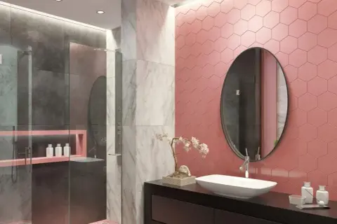 Bagno moderno con doccia, dove le piastrelle rosa a nido d'ape contrastano con il grigio e il marmo.