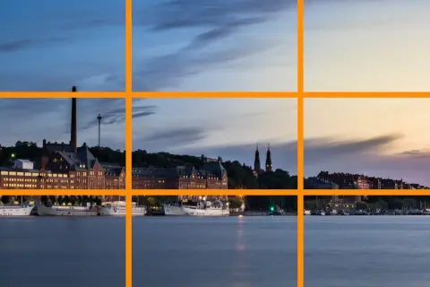 Pour comment prendre une belle photo, utilisez la règle des tiers pour cadrer ce paysage urbain au crépuscule avec des bateaux sur l'eau.