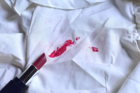 Roter Lippenstift auf weißem Stoff. So entfernst du eingetrocknete Make-up Flecken.