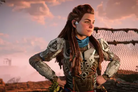 Aloy z Horizon Forbidden West, w zbroi z metalowymi płytami, patrzy w dal na tle zachodzącego słońca.