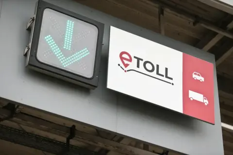 Znak e-TOLL z zielonymi strzałkami w dół i ikonami pojazdów.