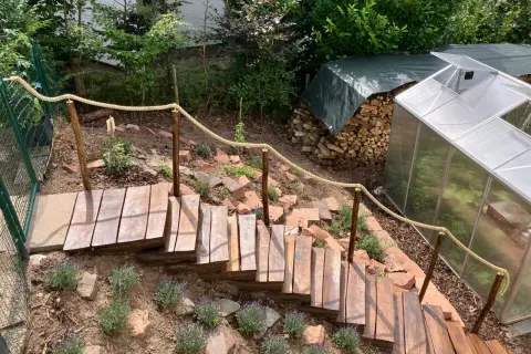 Eine **einfache Gartentreppe selber bauen** ist hier gelungen. Holzstufen mit Seilgeländer führen durch einen Hang mit Lavendel.