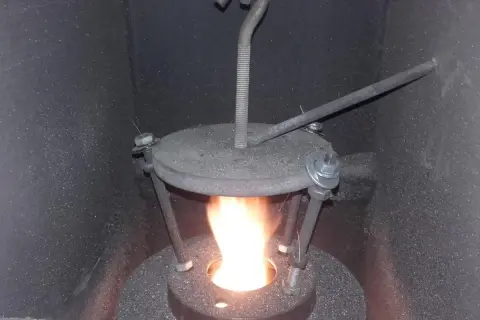 Płomień w piecu na ekogroszek. Widoczny metalowy deflektor z regulacją, który poprawia spalanie.